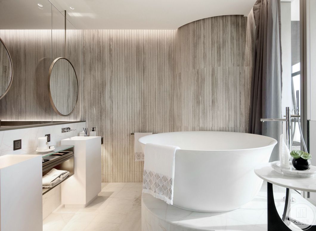 浴室浪漫简约，白色的浴缸被做成圆形，木质墙体和大理石地板起到了很好的互补作用，使得整体舒适又不乏质感，梳妆台旁毛巾和镜子一应俱全。
